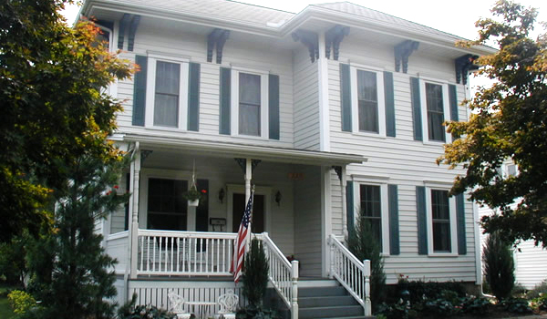 white house with white railing and green shutters