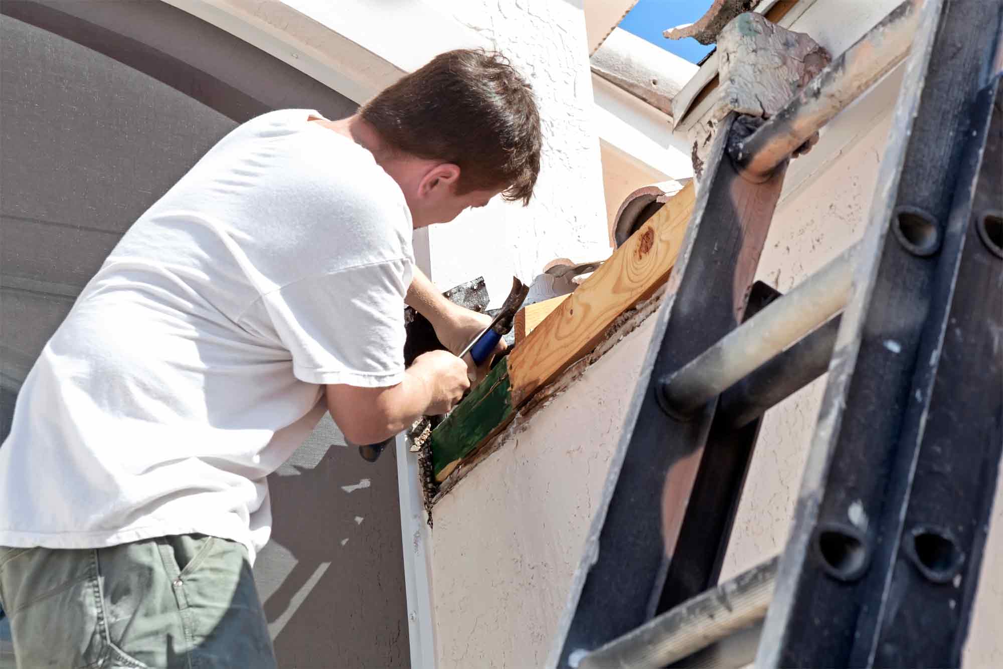 man repairing a gutter on a house